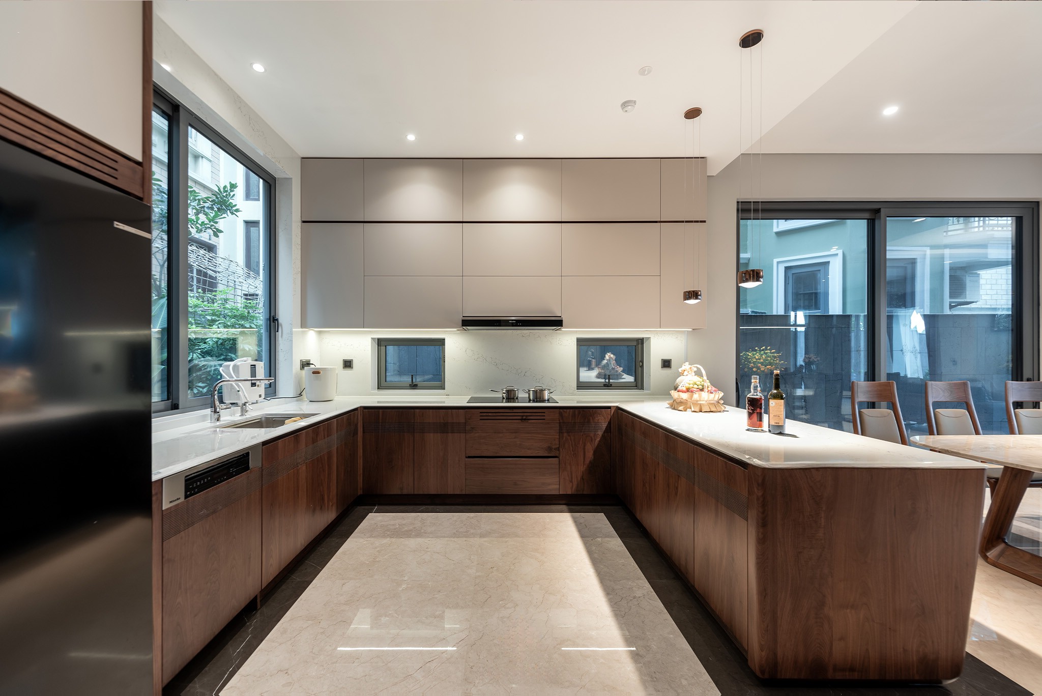 Mẫu tủ bếp dưới đẹp chữ L với bàn bar, gỗ óc chó nâu gụ và mặt đá granite trắng